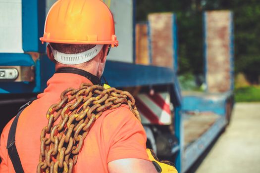 Oversize Load Concept. Caucasian Worker with Large Chain on His Shoulder. Transportation Industry.