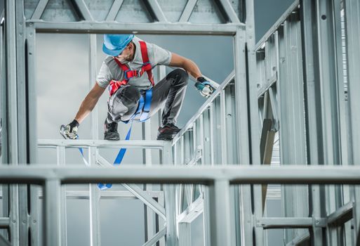 Caucasian Contractor Building Skeleton Steel Frame with Help of Safety Harness Equipment. Industrial Theme.