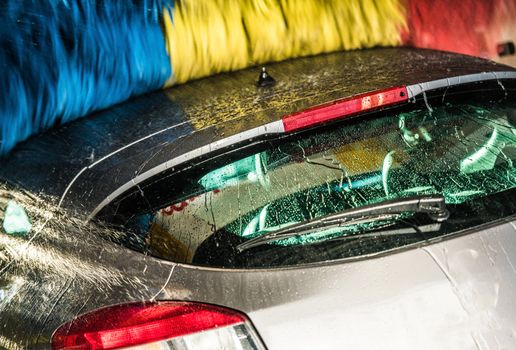 Modern Car in the Automatic Brush Car Wash. Closeup Photo. Vehicle Cleaning.