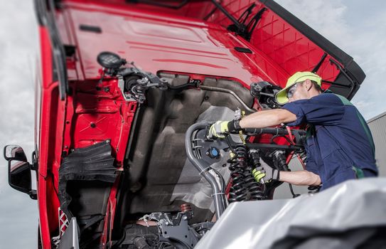 Semi Truck Under Maintenance. Caucasian Truck Mechanic Working to Fix the Tractor.