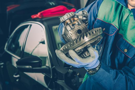 Caucasian Car Mechanic in His 30s with Part of Car Differential in Hands. Vehicle Service Theme.