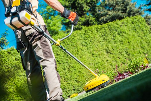 Gas String Trimmer Work. Caucasian Gardener with Power Tool in the Garden.