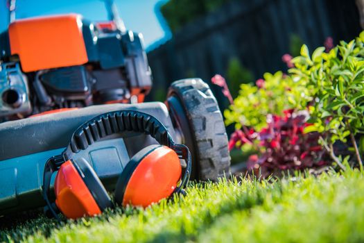 Hearing Protection While Working with Power Tools in the Garden. Ear Protectors and the Lawn Mower Closeup Photo.