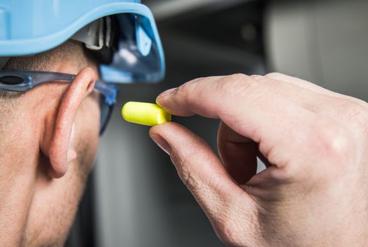 Ear Plugs Hearing Protection Simple Solutions. Factory Worker in Blue Hard Hat Preparing To Use Foamy Plug.