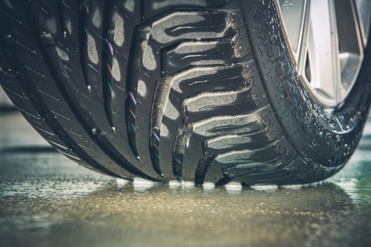 Brand New Vehicle Tire Tread Closeup Photo. Car Wheel on the Wet Pavement.