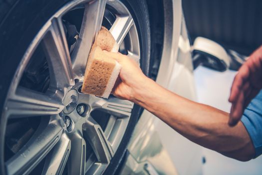 Men Cleaning Car Alloy Wheel. Vehicle Washing and Detailing Concept Photo.
