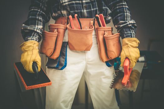 Construction Contractor on Duty Concept Photo. Worker with Large Tools Belt and Some Tools in Hands.