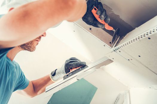 Drywall Finishing Patches. Apartment Remodeling by Caucasian Worker. Finishing Ceiling Elements.