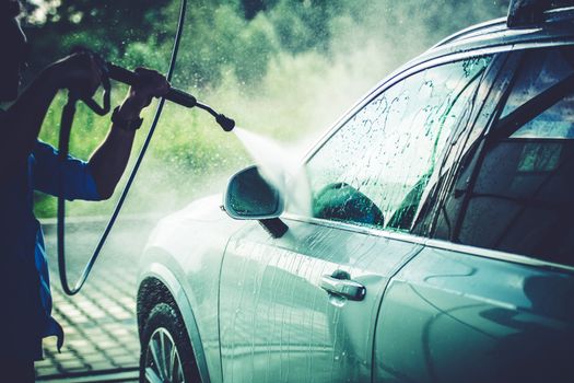 Men Cleaning His Vehicle in the Car Wash Using High Pressure Water Sprayer.