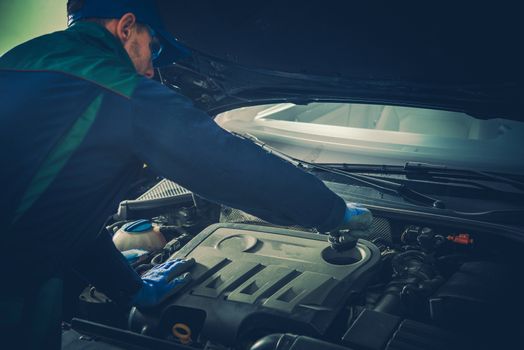 Vehicle Fluids Maintenance by Professional Car Mechanic. Caucasian Service Technician in His 30s.