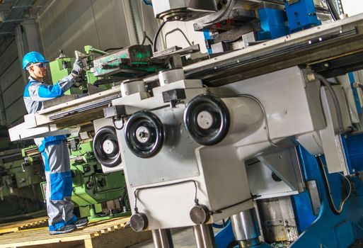 Heavy Duty Lathe Machinery Operator. Caucasian Metalworking Industry Worker in Front of the Machine.