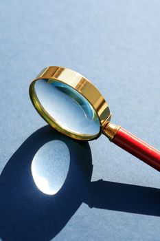 Nice retro magnifying glass under sunlight on gray background