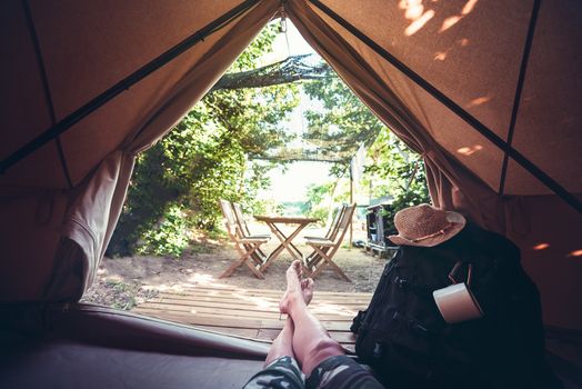 view of crossed legs of a hiker man resting barefoot in a camping tent, travel discovery concept, point of view shot