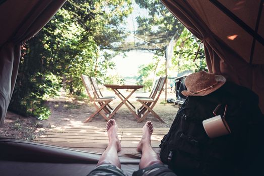 view of legs of a hiker man resting barefoot in a camping tent, travel discovery concept, point of view shot