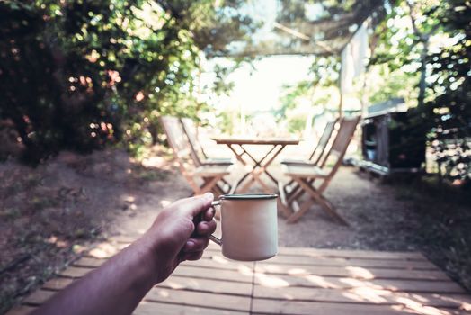 view of a hand of a hiker person resting with a cup in a camping, travel discovery concept, point of view shot