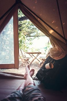 vertical view of crossed feet of a hiker man resting barefoot in a camping tent, travel discovery concept, point of view shot