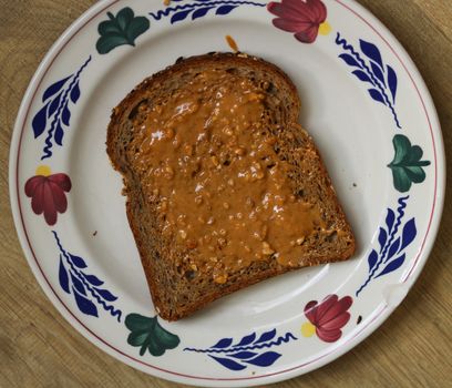 close up of Bread with peanut butter on white plate on wooden background