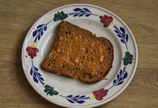 close up of Bread with peanut butter on white plate on wooden background