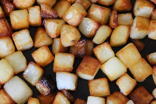 close up of baked potato cubes in pan in kitchen