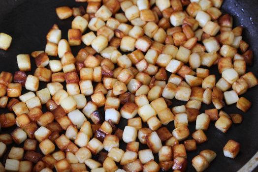 close up of baked potato cubes in pan in kitchen