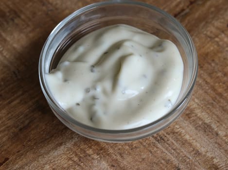 close up of garlic sauce in a glass bowl, on a wooden background