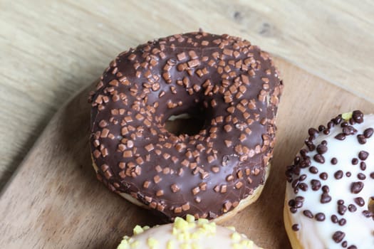 close up of a single strawberry donut with sprinkles on a wooden background