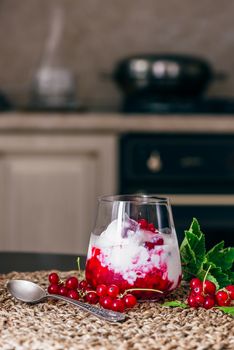 Ice Cream Dessert with Red Currant Jam and Fresh Berries. Kitchen on Background.