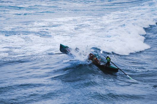 Brave men rowing into a crashing wave