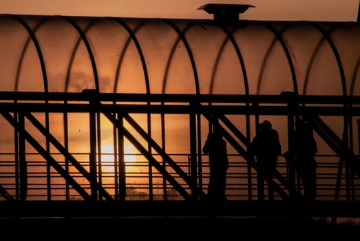 People standing in a walkway by sunset