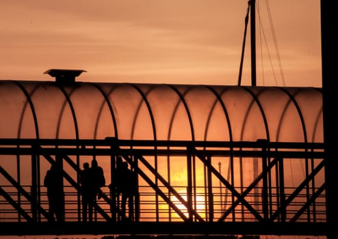 People standing in a walkway by sunset