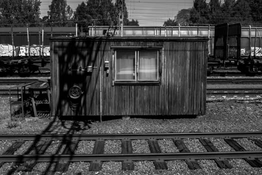 A small building by railroad tracks in black and white