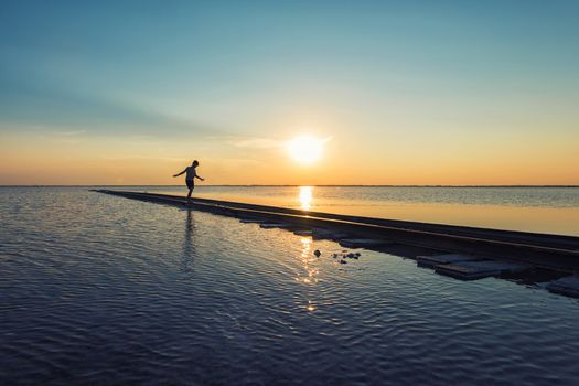 Boy on railway at beauty sunset on salty lake