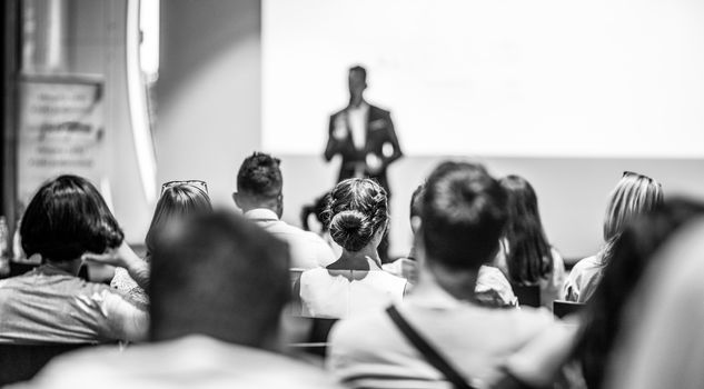 Speaker giving talk at business event. Audience at the conference hall. Business and Entrepreneurship concept. Focus on unrecognizable people in audience. Black and white photo.