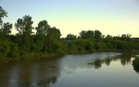 Calm flow of the river with reflection of clouds at sunset.