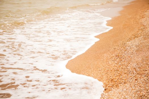 Atmospheric, melancholic mood, blurred background with copy space. View of shell beach and sea foaming waves. For design mockup, screensaver for device, content for social media. Horizontal