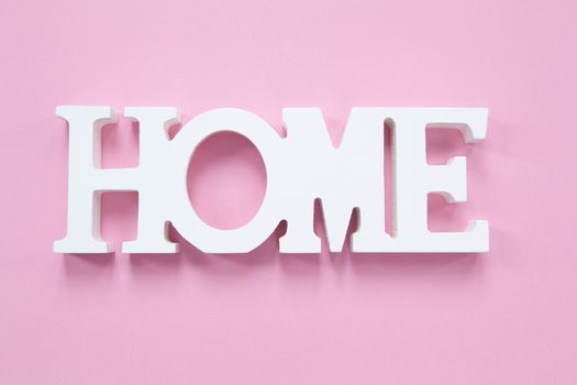 Decorative wooden word Home on a millennial pink background. Concept of home comfort, romance. Horizontal format. Flat lay