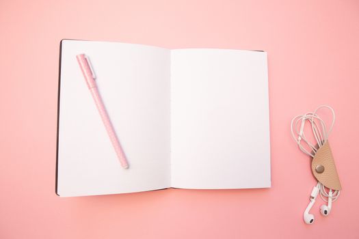Opened empty diary with pink pen on pastel millennial pink paper background. Concept education, blogging. Top view. Flat lay. Minimal style. Template for female blog. Lifestyle. Copy space.
