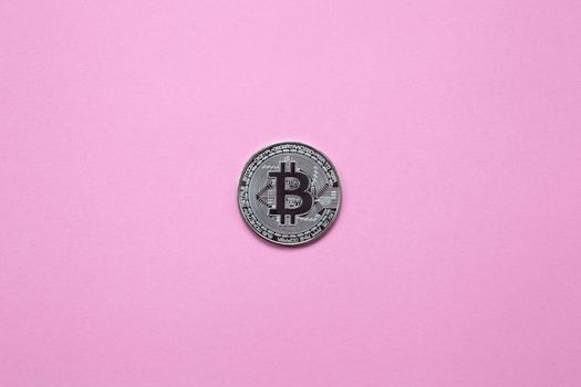 Silver bitcoin on a millennial pink background. Top view. Minimalism. Horizontal orientation.