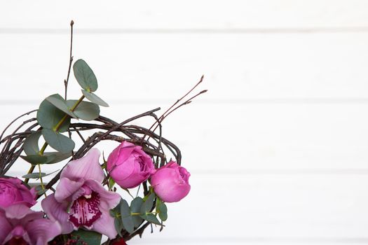 Creative flower bouquet on white wooden background. Focus on flowers, background is blurred. Mockup with copy space for greeting card, social media, flower delivery, Mother's day, Women's Day.