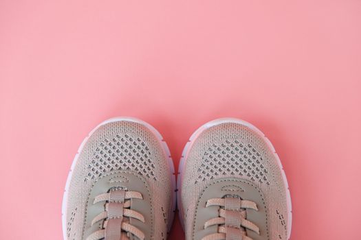 Sport, healthy lifestyle concept. New gray sneakers on pastel pink background. Copy space. Flat lay. Close-up.