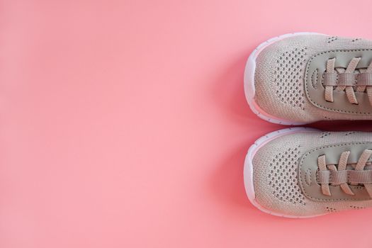 Sport, healthy lifestyle concept. New gray sneakers on pastel pink background. Copy space. Flat lay. Close-up.