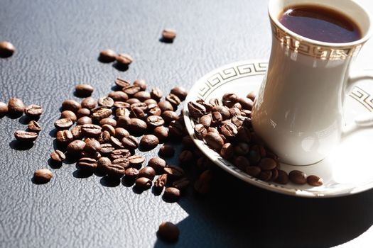 Elegance cup of black coffee near beans under sunlight
