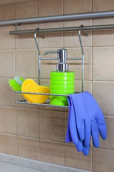 Utensils for washing dishes, liquid, gloves, brush, sponge on metal shelf in kitchen. Concept of decanting detergents, no labels and visual noise. Close-up. Modern interior. No people. Vertical.