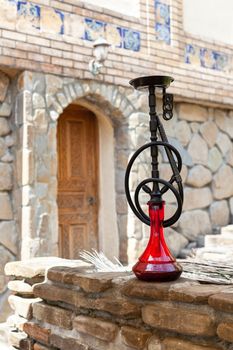 Black hookah with ruby bulb in authentic oriental antique cafe, outdoor. Front view, full length. Vertical.