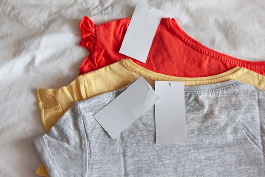 Three new kid's or women's t-shirt, grey, red, yellow colours, with clean label on white background. Concept shopping, summer sales, discounts, organic cotton clothes, recycled clothing
