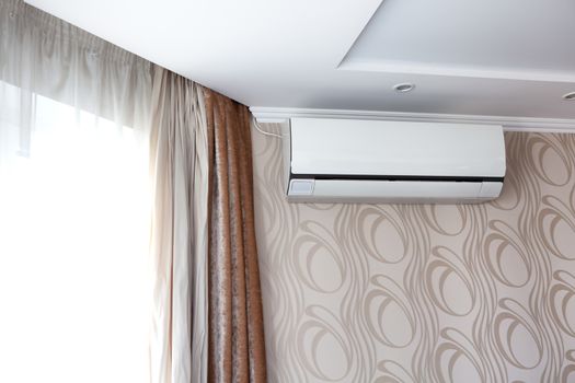 Air conditioning on the wall inside the room in apartment, switched off. Interior in calm beige tones