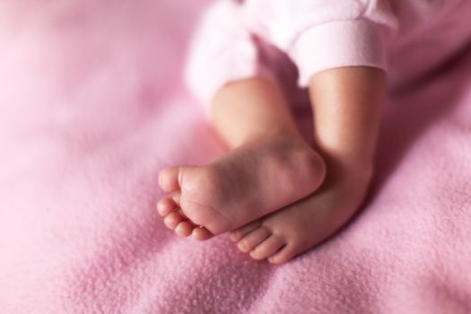 Little sweet legs of baby girl on pink background. Concept: kids, parenthood, family, baby shower, care. Copy space for text. Horizontal format. Selective focus. Close-up