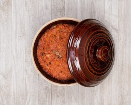 A ceramic pot of traditional Eastern European stewed cabbage on a white wooden kitchen board.