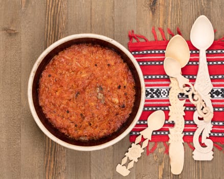 A ceramic pot of traditional Eastern European stewed cabbage and decorated wooden spoons on a brown wooden kitchen board.