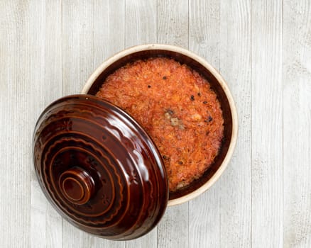 A ceramic pot of traditional Eastern European stewed cabbage on a white wooden kitchen board.